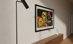 Framed artwork of a colorful robot and ghost on a wall above a wooden console table.