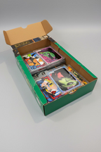 Box of custom stylized trading cards in protective plastic sleeves displayed inside an open art style cardboard box. The cards feature colorful street art style artworks, portraits and text.