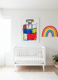 Nursery with a white crib, colorful abstract art, and a rainbow decoration on a white wall. Art by Mr. Clever Art