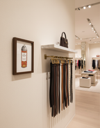 Belt rack with belts in a store setting, framed artwork on the wall.