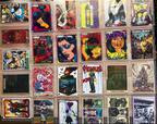 A grid of collectible trading cards displayed in clear protective cases, featuring various illustrated characters and comic-style artwork.